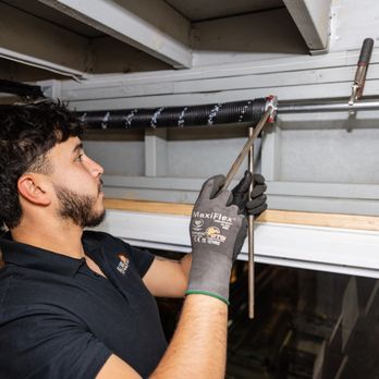 Technician performing preventive maintenance on a commercial door track